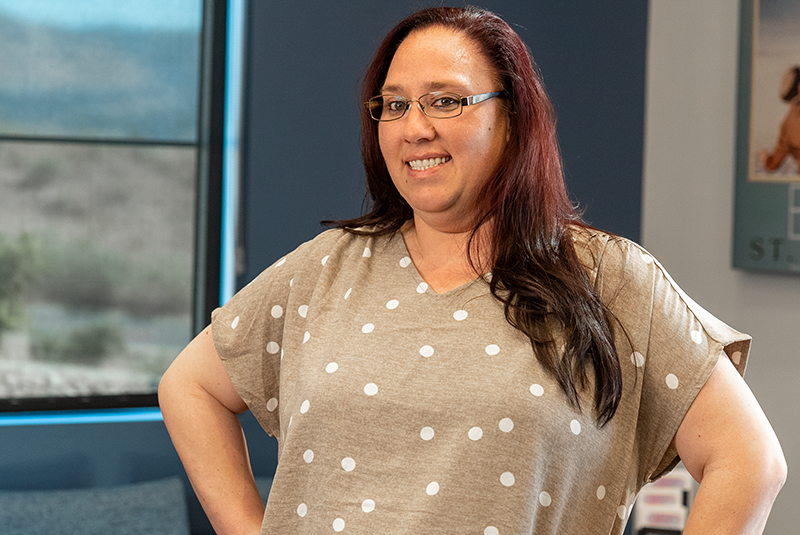 a Linrose Dental patient smiling with her arms on her hips